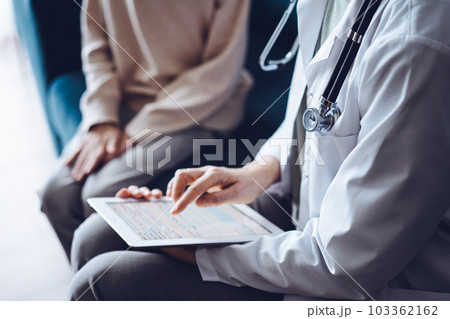 Doctor woman and kid boy patient at home. The pediatrician using tablet computer while filling up medical records, close up. Medicine, healthcare concept Doctor woman and kid boy patient at home. The pediatrician using tablet computer while filling up medical records, close up. Medicine, healthcare concept 103362162