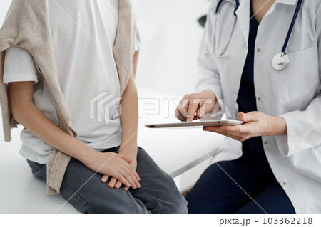 Doctor and child patient. The doctor is using tablet computer and is ready to examine the boy. The concept of ideal health in medicine 103362218