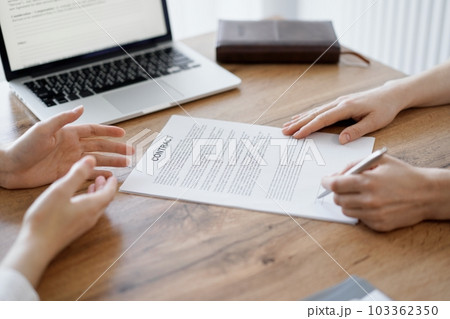 Business people signing contract papers while sitting at the wooden table in office, closeup. Partners or lawyers working together at meeting. Teamwork, partnership, success concept Business people signing contract papers while sitting at the wooden table in office, closeup. Partners or lawyers working together at meeting. Teamwork, partnership, success concept 103362350