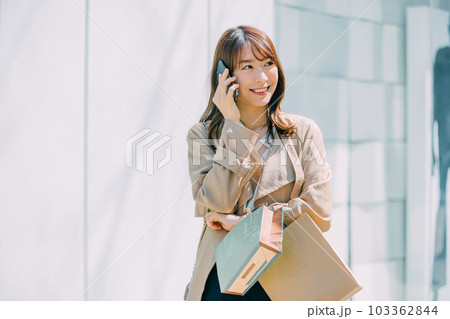 スマホで話しながらショッピングをする笑顔の日本人女性 103362844
