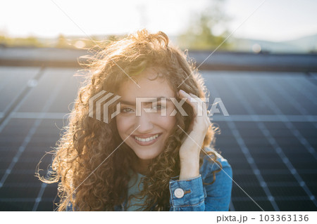 Portrait of young woman on roof with solar panels. 103363136