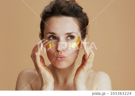 modern female with eye patches against beige background modern female with eye patches against beige background 103363224