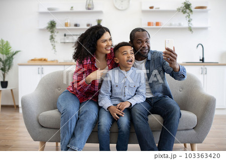 Spouses with son having online phone call in lounge at home Spouses with son having online phone call in lounge at home 103363420