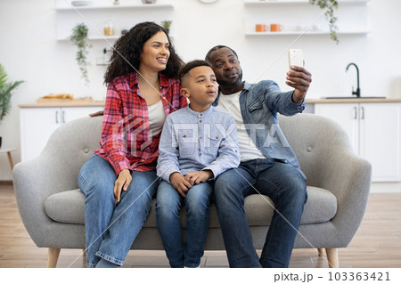 Family of three taking video call via mobile at home Family of three taking video call via mobile at home 103363421