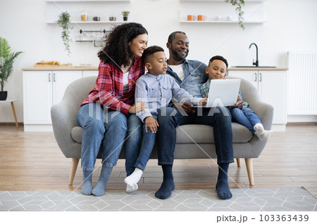 Four-person family watching movie on laptop at home Four-person family watching movie on laptop at home 103363439