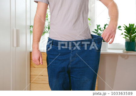 The guy is trying on big jeans after losing weight The guy is trying on big jeans after losing weight 103363589