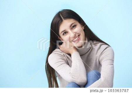 studio portrait of a beautful caucasian woman, sitting on floor, looking at camera smiling,  103363787