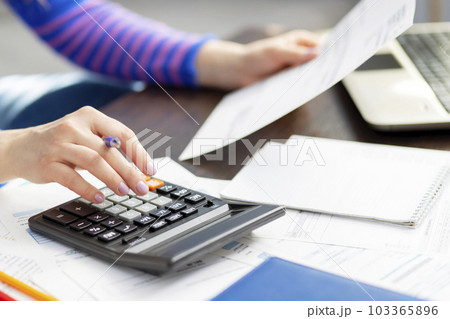 Woman using calculator for calculate domestic bills at home, doing paperwork Woman using calculator for calculate domestic bills at home, doing paperwork 103365896