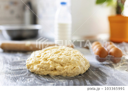 Homemade dough, rolling pin and baking ingredients on a wooden table in kitchen 103365991