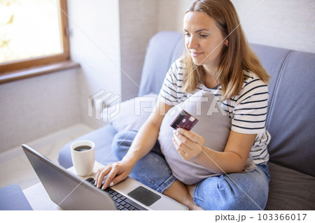 Young woman holding credit card and using laptop computer Young woman holding credit card and using laptop computer 103366017