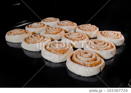 Twelve uncooked cinnamon buns baking in electric oven 103367720