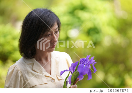 花を持ってたたずむ素顔の中年女性 103367872