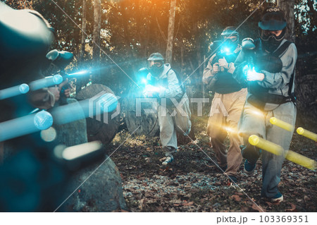 Teams playing paintball outdoors Teams playing paintball outdoors 103369351