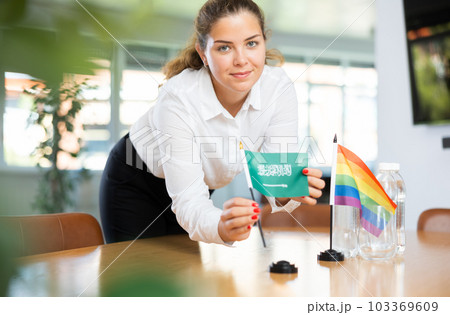 Young lady sets miniatures flags of LGBT and Saudi Arabia before international negotiations Young lady sets miniatures flags of LGBT and Saudi Arabia before international negotiations 103369609