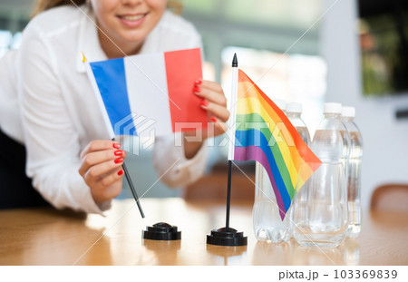 Unrecognizable girl sets midget flags of LGBT and France before international negotiations 103369839