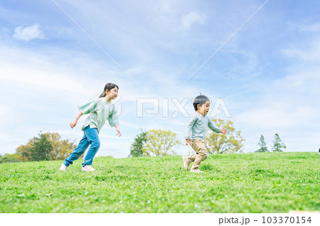 芝生の丘を走る姉弟 103370154