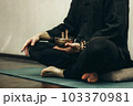 man sits with his legs folded and holding a copper singing bowl with sticks in his hands. Relaxation and meditation. Alternative medicine tibetan singing bowls 103370981