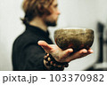 A man holds a singing bowls on his outstretched hand. Music of Tibetan singing bowls. Himalayan bowls. Making sound. 103370982