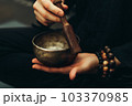 Close-up of hands with rosary playing on singing bowls. Relaxation and meditation. Alternative medicine. Tibetan and Himalayan singing bowls. Make a sound. 103370985
