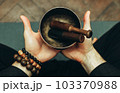 Close-up two hands of a man holding singing bowls with sticks in front of him. Listen to the healing vibrations of Tibetan bowls. Humility and calm. Rosary on the hand 103370988