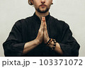 A man in black shirt sitting folded palms together, doing yoga. Hands folded in prayer. Hands together. Prayer, gratitude. Yoga hand pose. Folded hands. Palm pressed. Close up 103371072