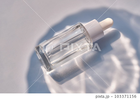 Serum bottle on a blue background with glare. 103371156