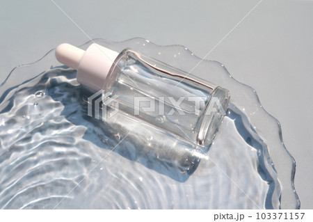 A bottle of serum in water on a blue background. 103371157
