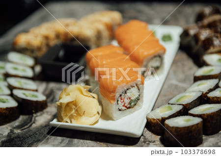 Tasty sushi rolls, wasabi, ginger and soy sauce on black gray table Tasty sushi rolls, wasabi, ginger and soy sauce on black gray table 103378698