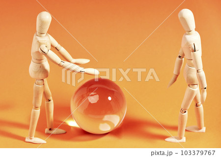 Dummies in front of a crystal ball on an orange background 103379767