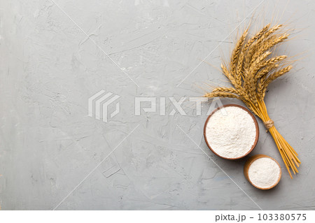 Flat lay of Wheat flour in wooden bowl with wheat spikelets on colored background. world wheat crisis 103380575