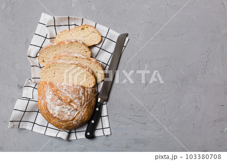 Freshly baked bread cut with knife on a wooden board. top view Sliced bread and knife 103380708