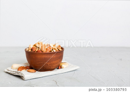 mixed nuts in bowl. Mix of various nuts on colored background. pistachios, cashews, walnuts, hazelnuts, peanuts and brazil nuts 103380793