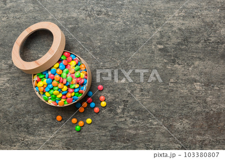 Set of different sweet candy in a paper box with a satin ribbon on a colored background. Holiday concept Set of different sweet candy in a paper box with a satin ribbon on a colored background. Holiday concept 103380807