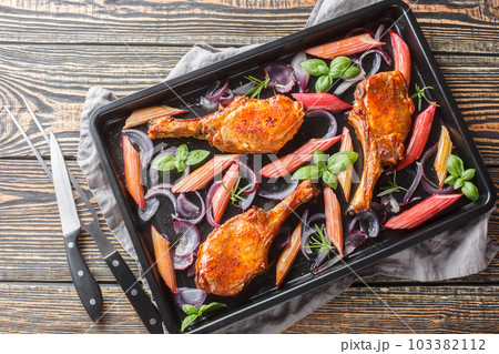Baked pork chops with red onions, herbs and rhubarb in honey glaze close-up in a baking sheet. Horizontal top view Baked pork chops with red onions, herbs and rhubarb in honey glaze close-up in a baking sheet. Horizontal top view 103382112
