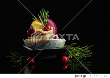 Herring fillet in oil with lemon, onion, rosemary, and cranberries. 103382850