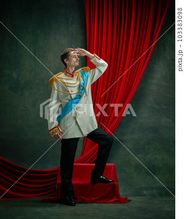 Portrait of young man, royal person, king, duke on elegant costume, standing with noble look against dark green, vintage background 103383098