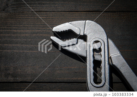 Chrome plumbing wrench on dark wood texture background 103383334