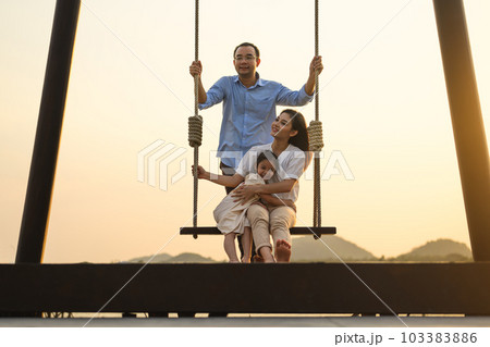 Family enjoying with outdoor activities sitting on swing with sunset Family enjoying with outdoor activities sitting on swing with sunset 103383886