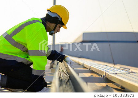 Worker with safety helmet checking and operating system at solar cell farm  103383972