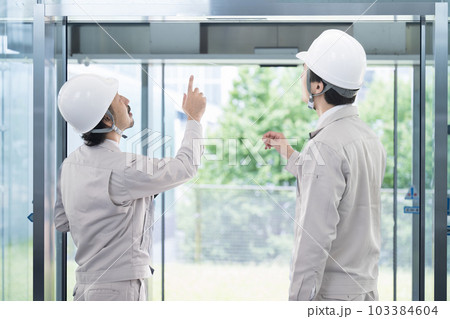 ビルや設備の点検指を差して確認やメンテナンスをする作業員 103384604