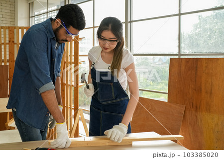 Female carpenter and male worker happy and making furniture in carpentry shop Female carpenter and male worker happy and making furniture in carpentry shop 103385020