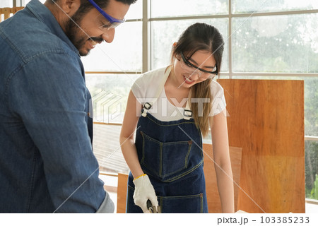 Female carpenter and male worker happy and making furniture in carpentry shop Female carpenter and male worker happy and making furniture in carpentry shop 103385233