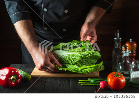 A professional chef makes a fresh napa cabbage salad. Preparation for slicing in the restaurant kitchen. Vegetable diet idea 103386358