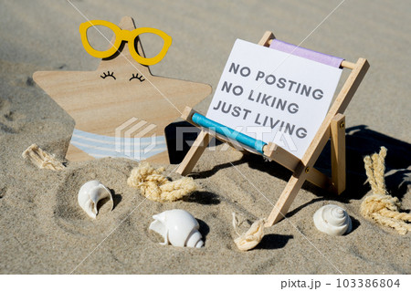 NO POSTING NO LIKING JUST LIVING text on paper greeting card on background of beach chair lounge starfish summer vacation decor. Concept of social media technology detox Sandy beach sun. Holiday 103386804