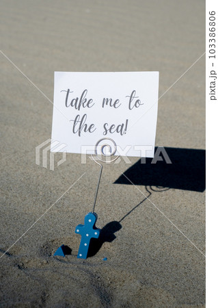 TAKE ME TO THE SEA text on paper greeting card in anchor paper holder and starfish seashell summer vacation decor. Sandy beach sun coast. Holiday concept postcard. Getting away Travel TAKE ME TO THE SEA text on paper greeting card in anchor paper holder and starfish seashell summer vacation decor. Sandy beach sun coast. Holiday concept postcard. Getting away Travel 103386806