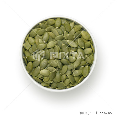 Bowl with green pumpkin seeds isolated on white background. Top view. Round plate 103387851