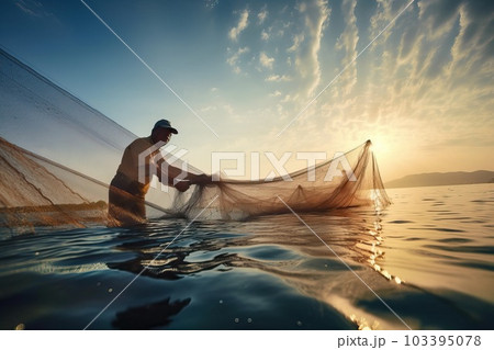 A male fisherman stands knee-deep in water and - Stock