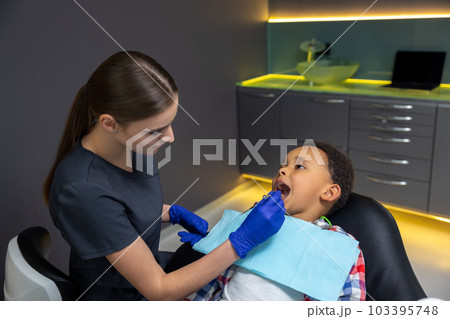 Female doctor checking up dark-skinned boy Female doctor checking up dark-skinned boy 103395748