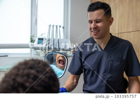 Doctor giving mirror to dark-skinned boy Doctor giving mirror to dark-skinned boy 103395757