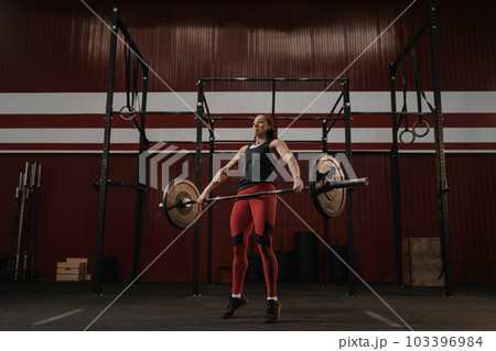 Crossfit woman lifting heavy barbell at the gym. Crossfit woman lifting heavy barbell at the gym. 103396984